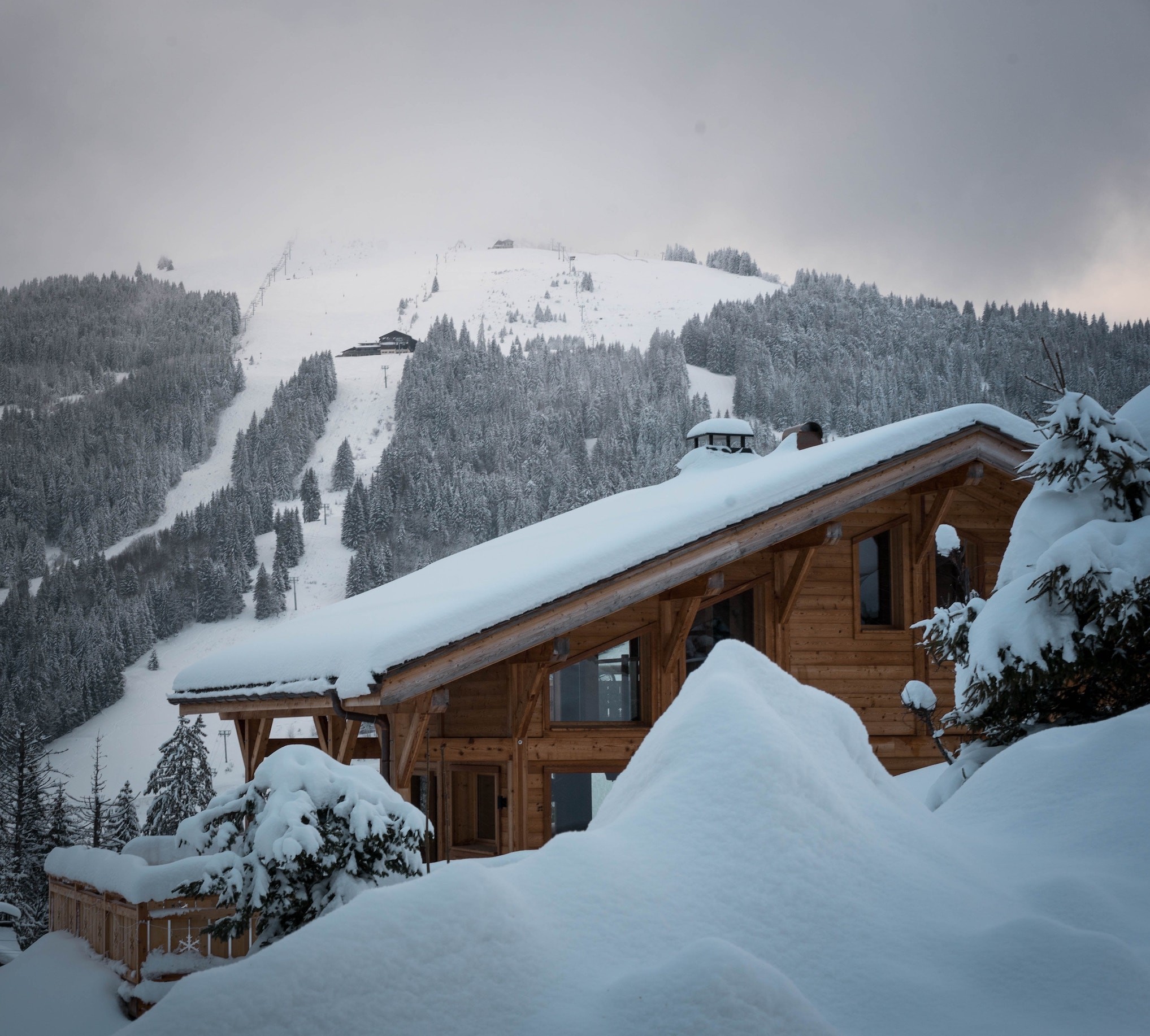 A modern chalet is covered in snow on a snowy slope