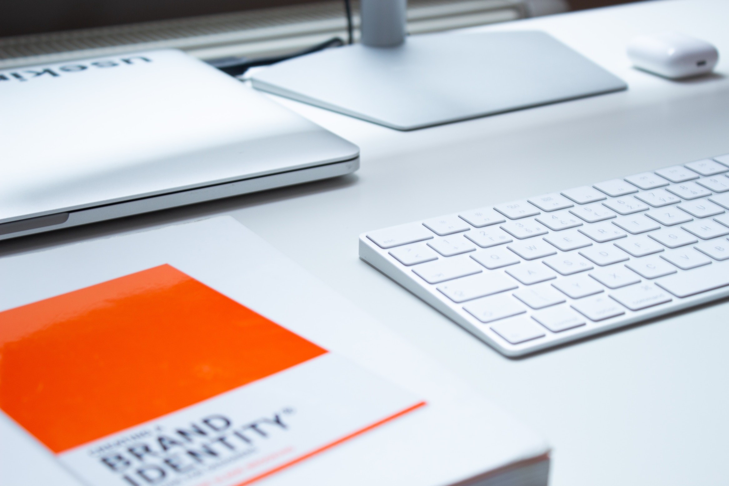 A white desk with a laptop and a book on it, showcasing hospitality branding.