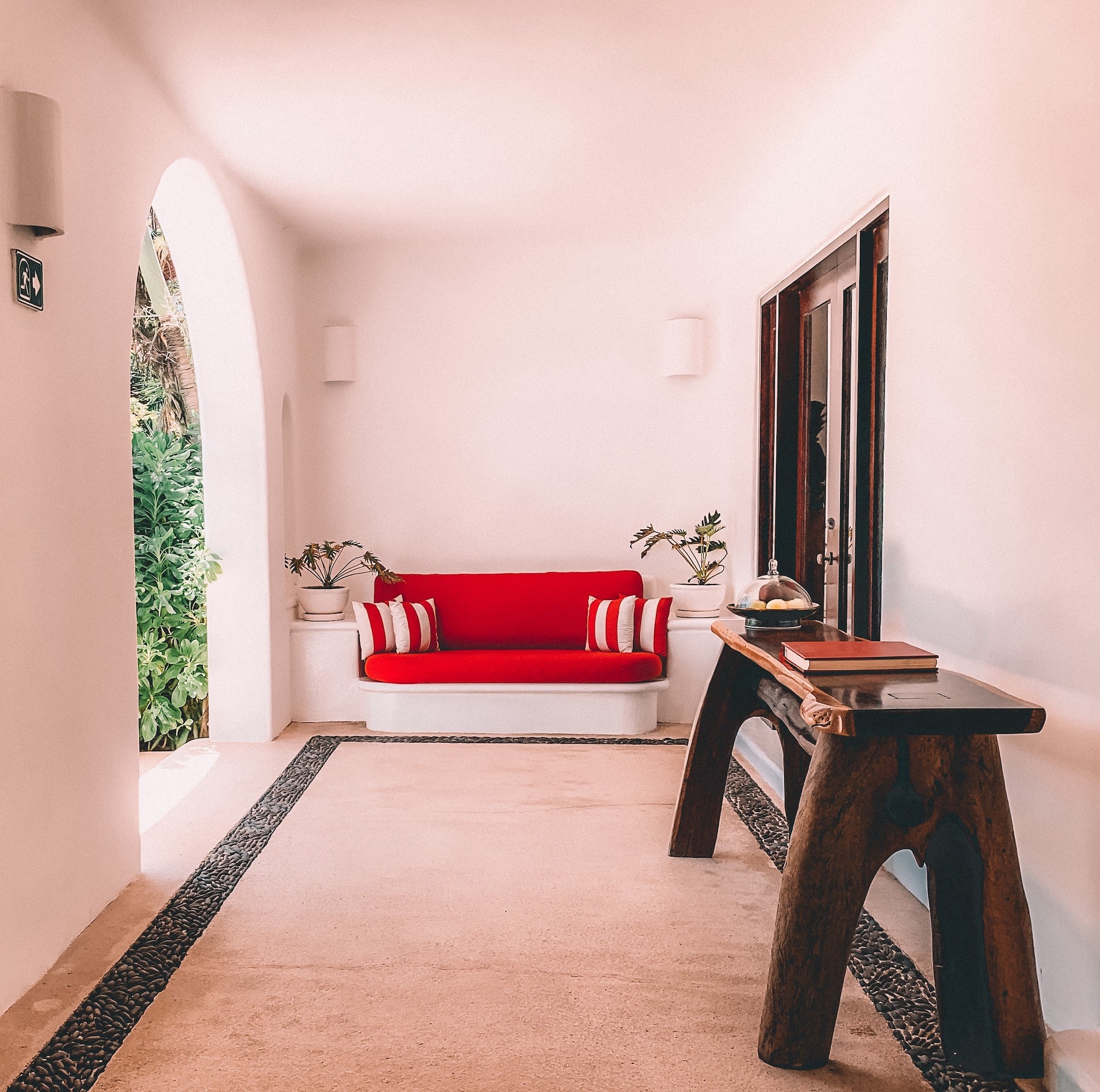 A boutique hotel hallway with a red couch and a table