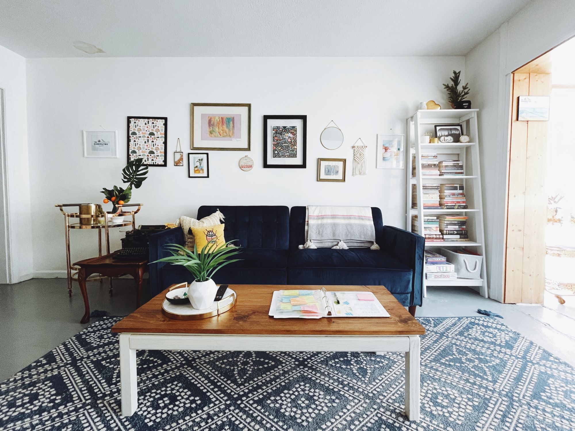 An airbnb host's living room with a blue couch and a rug.