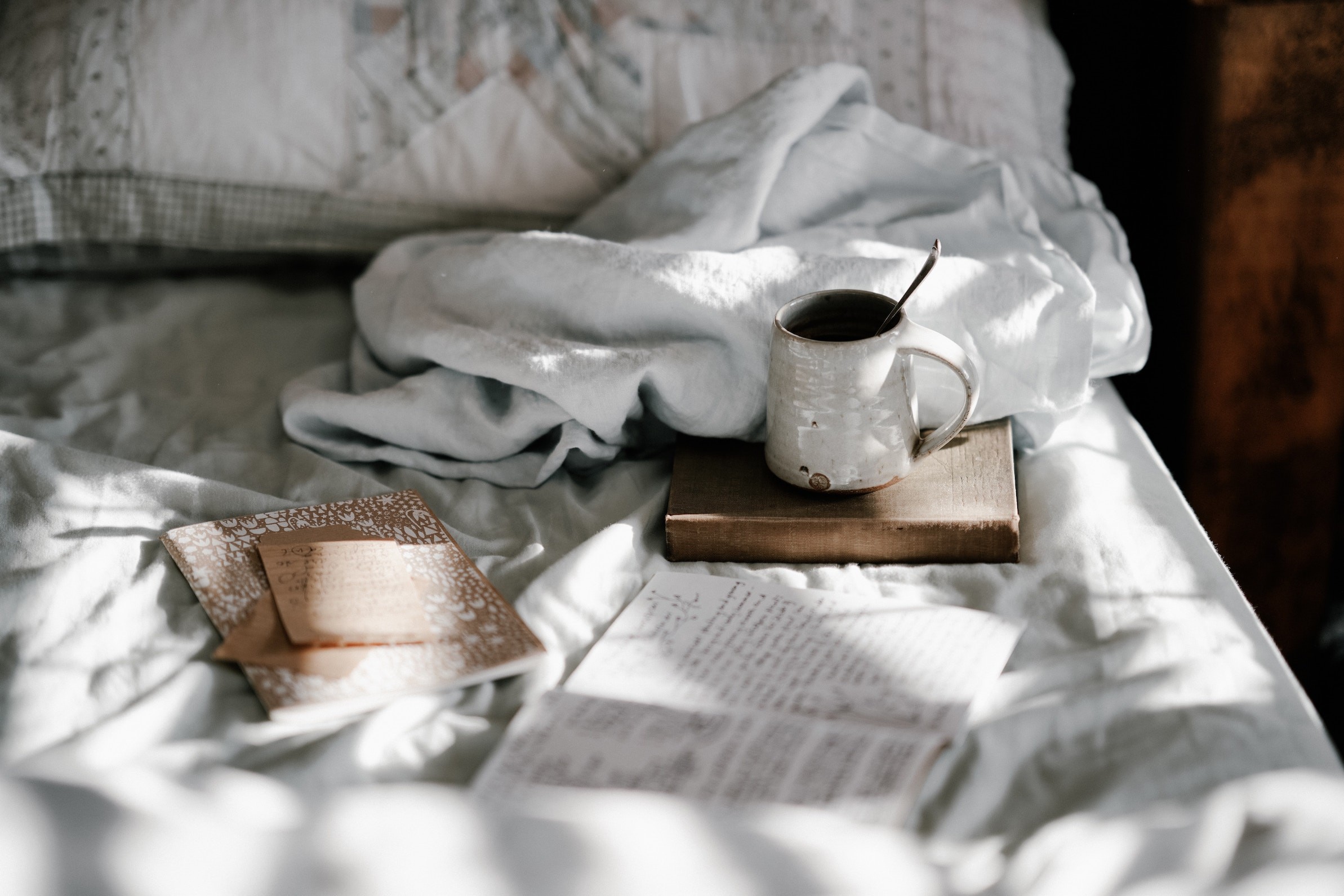A cup of coffee and a book on a bed, perfect for a cozy morning in a bed and breakfast.