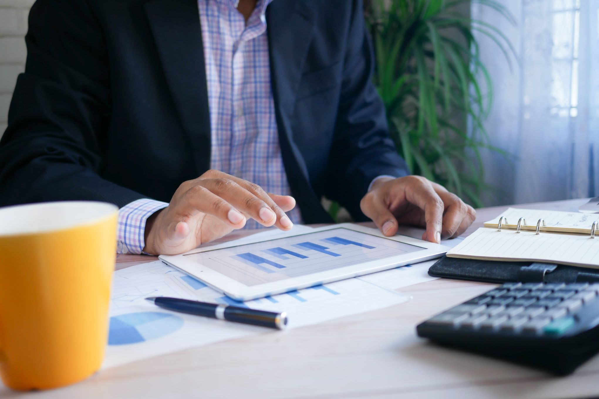 A businessman utilizing yield management techniques with a tablet at his desk